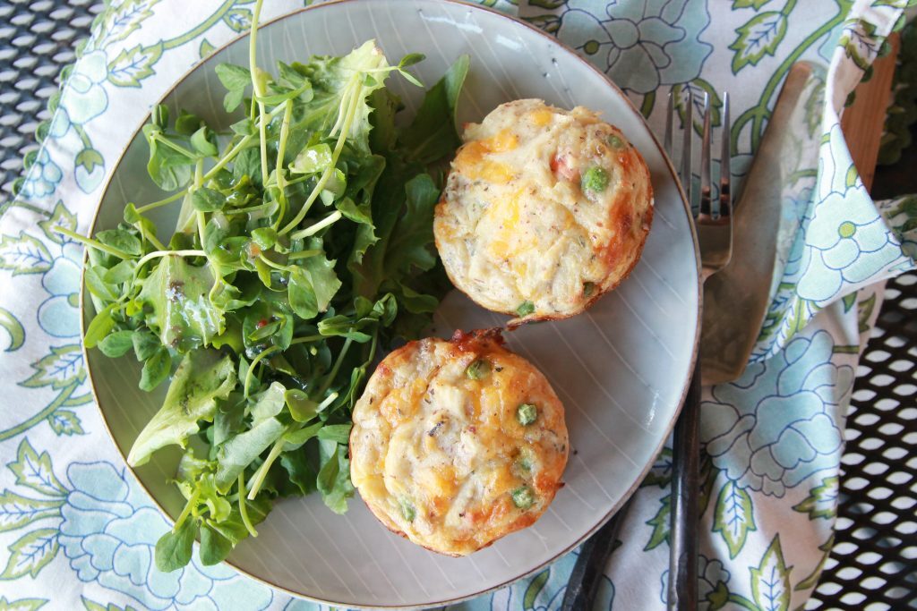 mini chicken pot pie biscuits with green salad on a round plate with fork and knife.