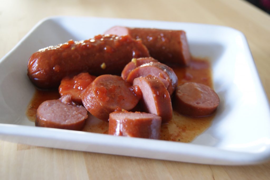 Slow cooked sliced BBQ sausage served on a white plate.