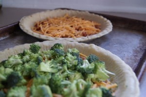 Two pans of bacon ranch quiche, one topped with broccoli, the other topped with cheese.