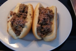 Ground meat placed on two white hot dog buns on a white plate.
