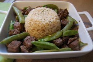 Slow cooked Asian spiced beef served with edamame and brown rice on a white dish.