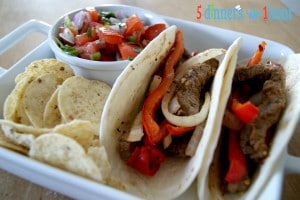 Beef fajitas tacos with seasoned bell peppers and onions, on flour tortillas, served with a side of tortilla chips and pico.