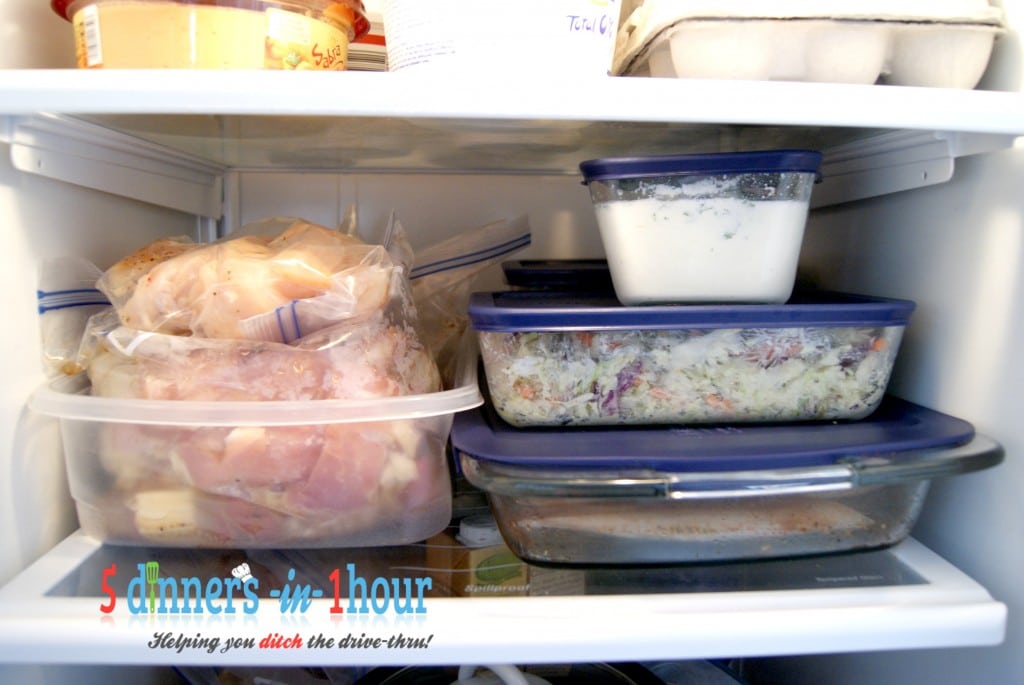 Five different dinners all prepped and in containers inside of a refrigerator.