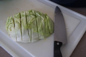 Sliced cabbage on a white cutting board with a knife.