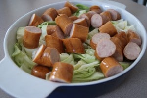 Chopped sausage and cabbage in a blue baking bowl ready to be cooked.