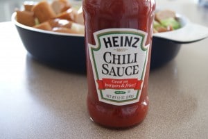 A bottle of Heinz chili sauce, that is ready to be drizzled over the sausage and cabbage.