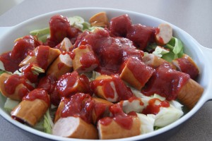 Sausage and chopped cabbage, drizzled with chili sauce ready to be baked.