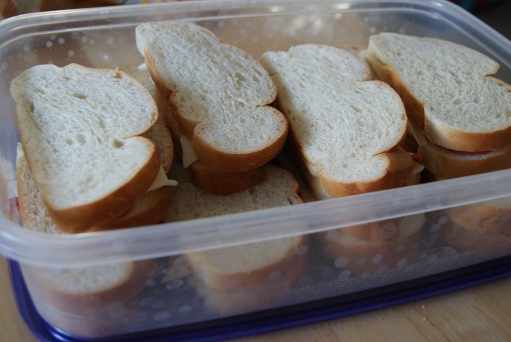 French bread sandwiches with pepperoni and provolone cheese in a container.