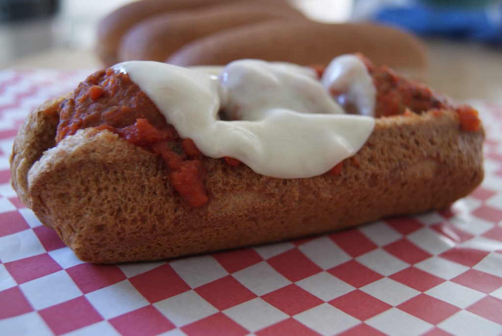 Meatball sub with marinara sauce and sliced cheese served on a whole wheat sub bun.