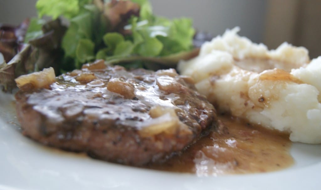 Salisbury steak with brown gravy served with mashed potatoes and green salad.