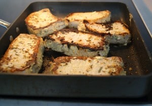 Slices of pork being browned on a skillet on top of the stove.