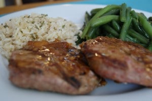 Grilled orange glazed turkey patties served with rice and green beans on a white plate