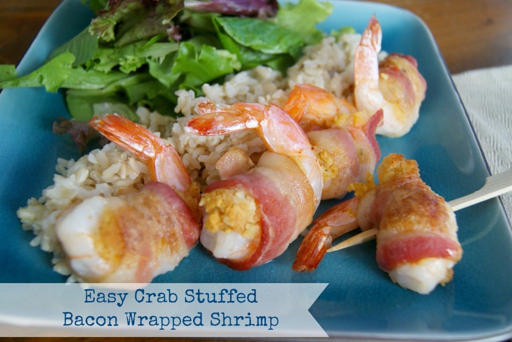 Baked crab stuffed shrimp wrapped in bacon, served with brown rice and salad on a blue plate.