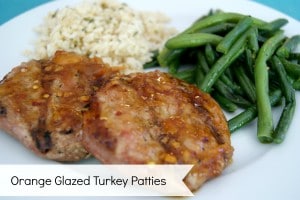 orange glazed turkey patties on a white dish, served with green beans and rice.