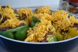 Bell peppers stuffed with refried beans and covered with cheese in a baking dish.