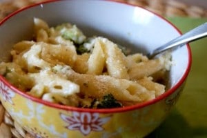 A bowl of pasta with broccoli mixed in.