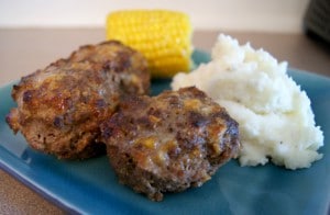 Two pieces of meatloaf served with a side of mashed potatoes and a petite ear of corn.