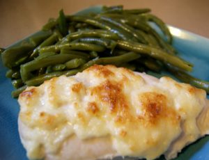 Chicken topped with artichoke sauce, with a side of green beans.