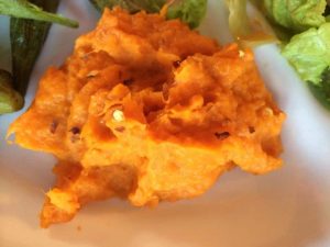 mashed sweet potatoes served on a plate topped with red pepper flakes.