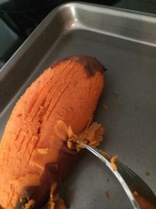 Oven roasted sweet potato being peeled by a fork.