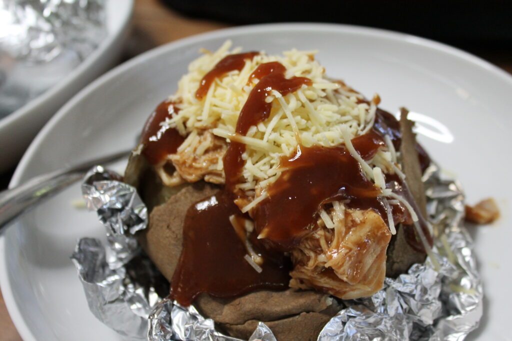 shredded chicken on baked potatoes with bbq sauce