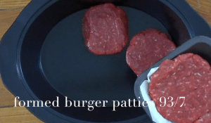Hamburger patties being placed in a slow cooker