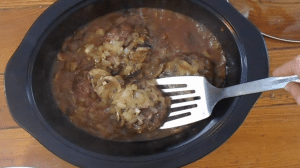 Cooked Salisbury Steak in a brown gravy with onions and mushrooms