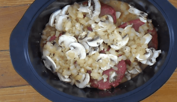 Crockpot with layered hamburger patties and mushrooms for salisbury steak.