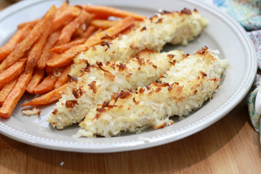 Coconut covered chicken strips, served with sliced baked carrots, all served on a plate.