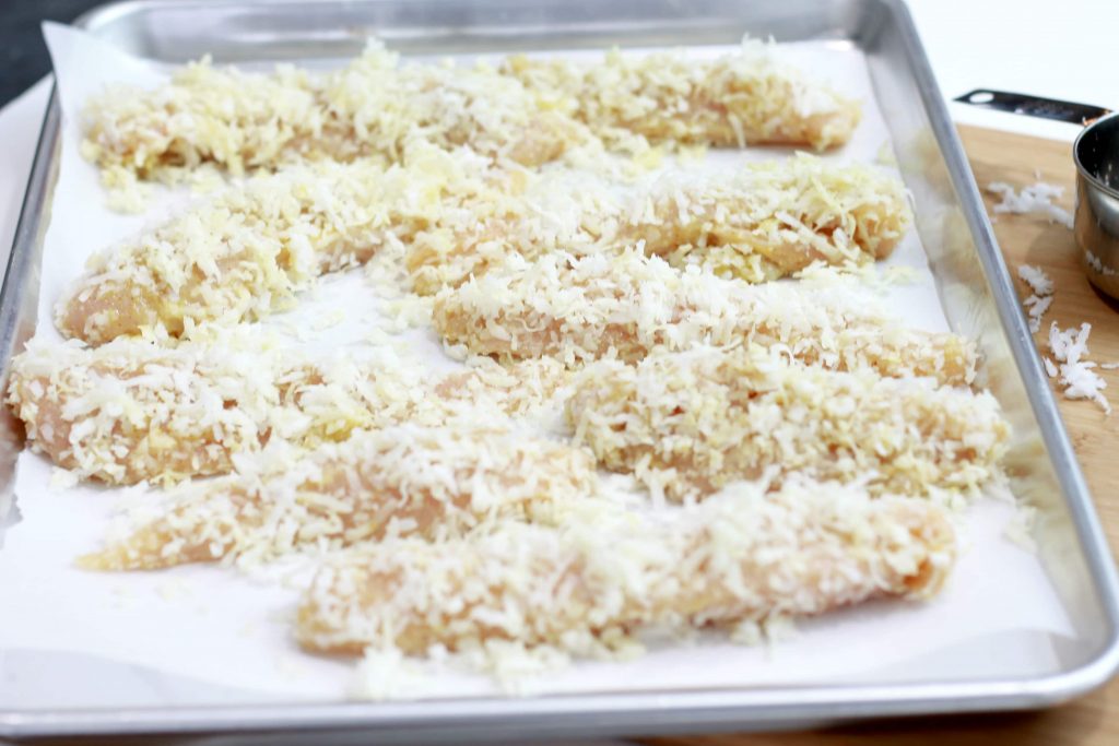 Chicken strips, in a sheet pan, dressed with coconut shavings.
