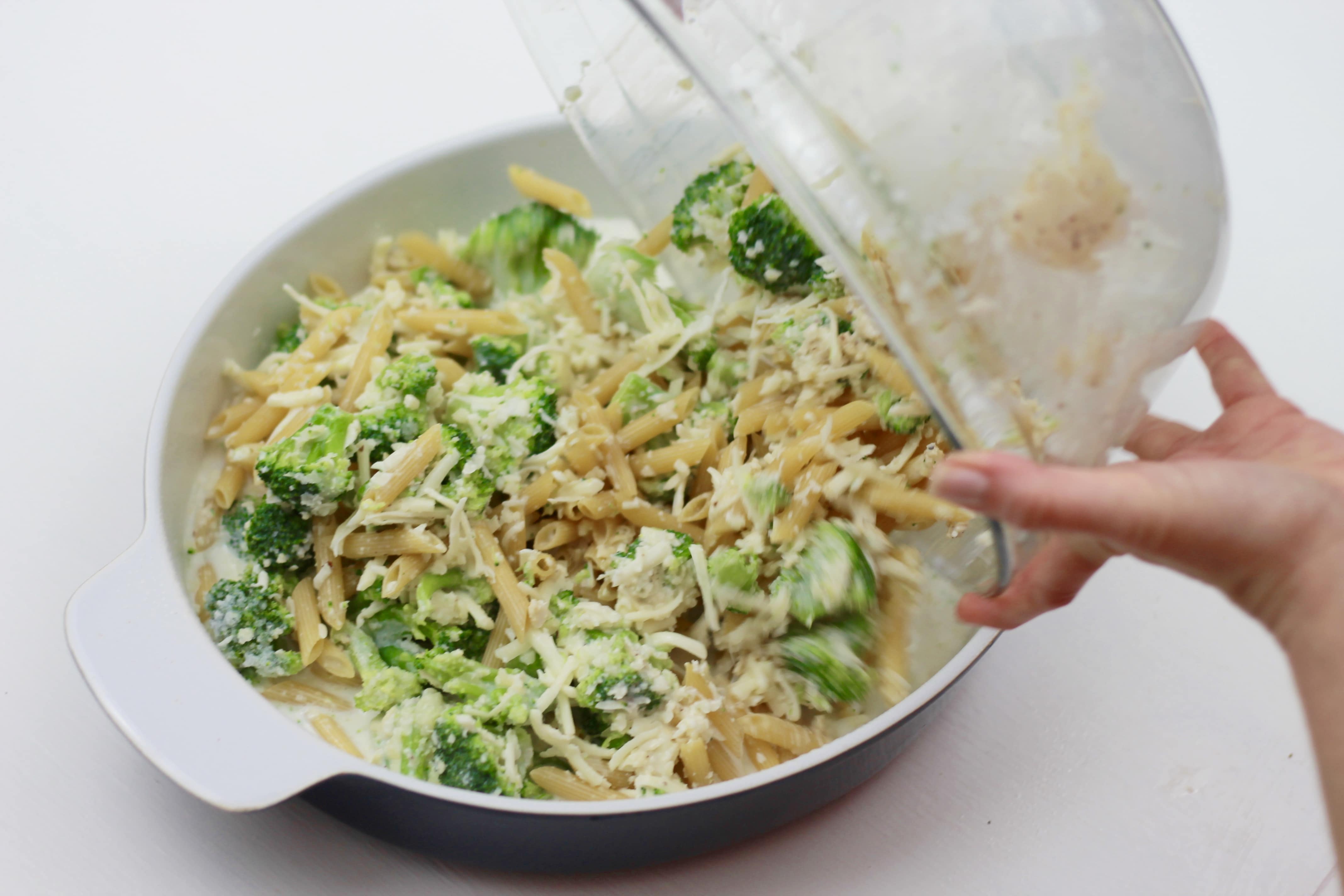 Broccoli, pasta, and shredded cheese all mixed together and poured into a dish to be cook in the oven.
