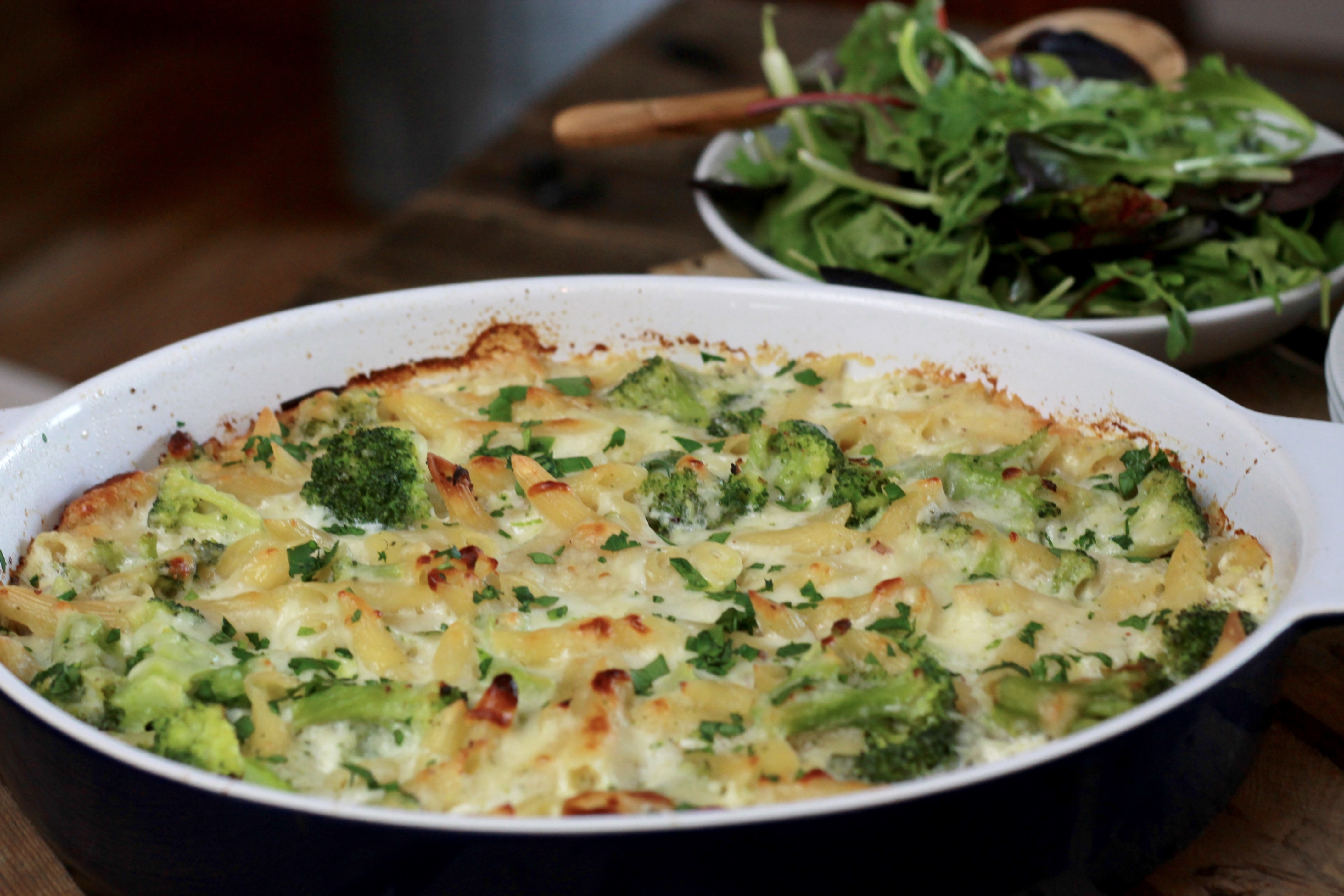 Oven baked crisp pasta, broccoli, and cheese in a dish to be served, with a side salad.
