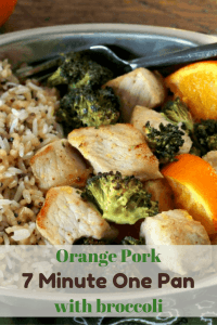 Orange chicken, with broccoli, and cooked diced oranges served with a side of brown rice in a silver dish ready to be eaten.