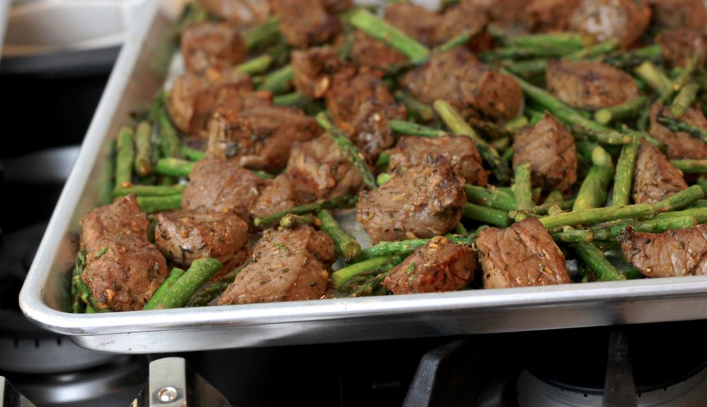 Sheet pan with broiled spicey steak bites and asparagus.