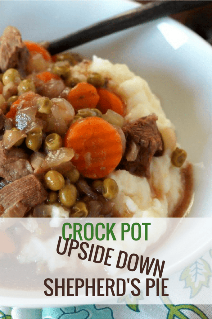 Steak bites, sliced carrots, peas, served on top of mashed potatoes in a white bowl ready to be eaten.