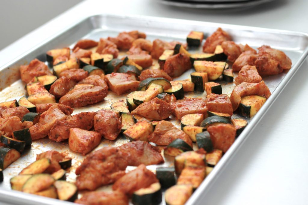 Cucumber, chicken marinated and placed on a sheet pan for cooking.