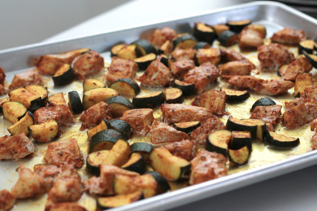 Cooked marinated chicken,and cucumbers all on a sheet pan ready to be served.