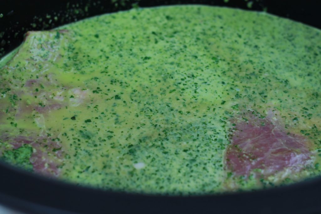 Marinated flank steak placed into a crock pot with chopped onions ready to cook