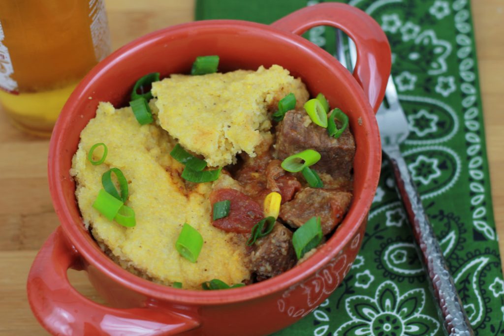 BBQ beef and corn bread topped with chives served in a red bowl ready to be eaten.