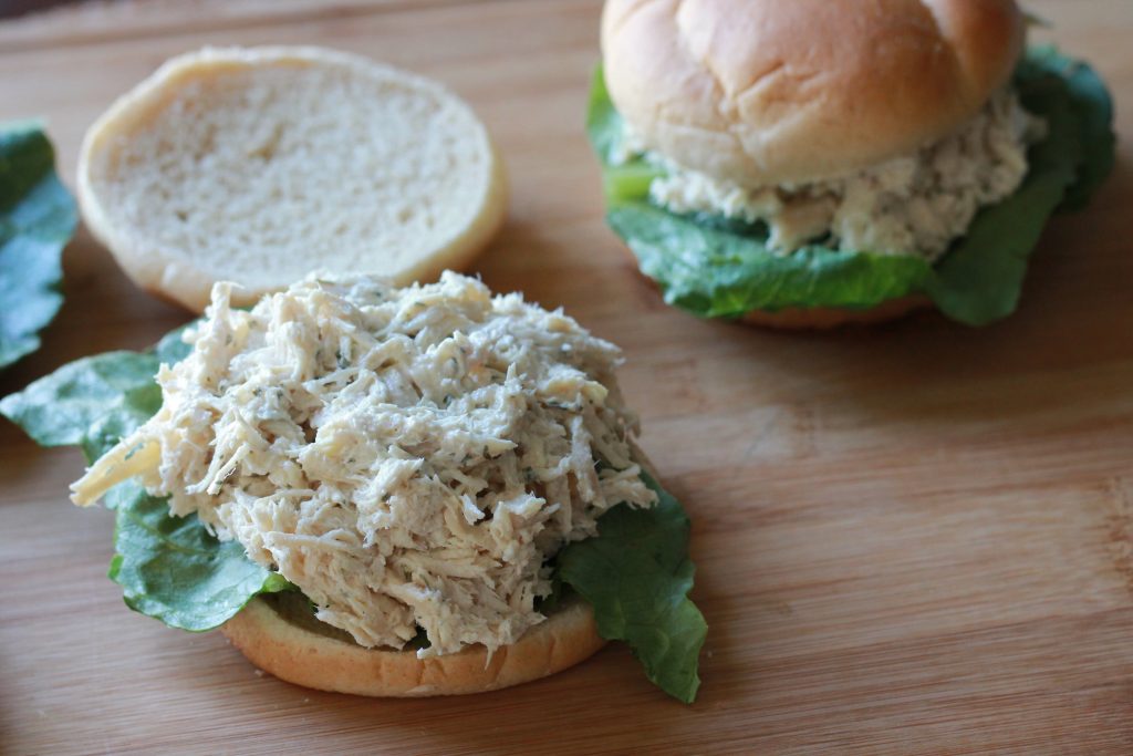 slow cooked chicken caesar salad on hamburger bun with lettuce.