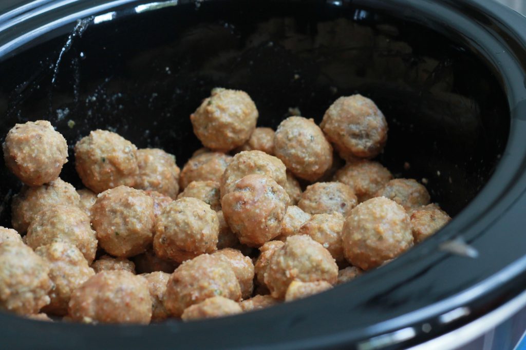 frozen meatballs in a black crockpot waiting to be cooked.