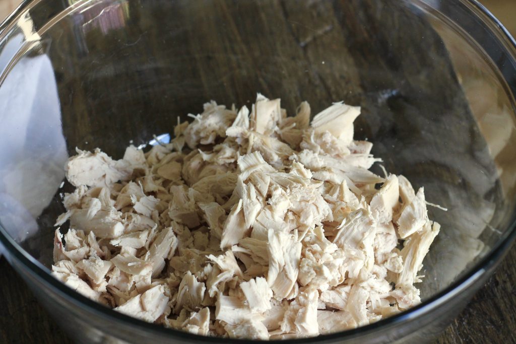 shredded roasted chicken in a clear bowl.
