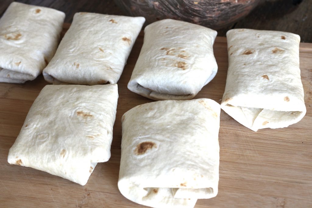 several shredded chicken burritos all wrapped up and ready to eat