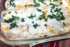 Close up of baked sour cream chicken enchiladas in a glass baking dish.