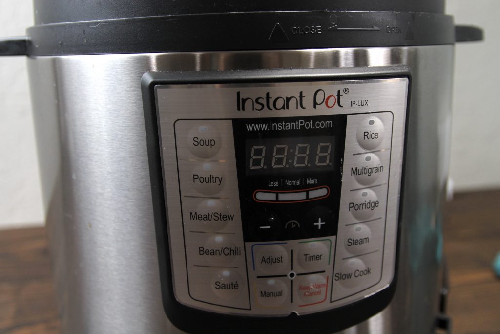 silver stainless steel instant pot pressure cooker on a wooden counter top.