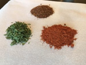 Three different spices and herbs placed on parchment paper ready to be used to season your food.