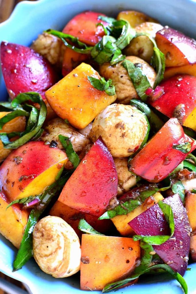 Sliced peaches, lettuce, and petite potatoes together and served on a plate.