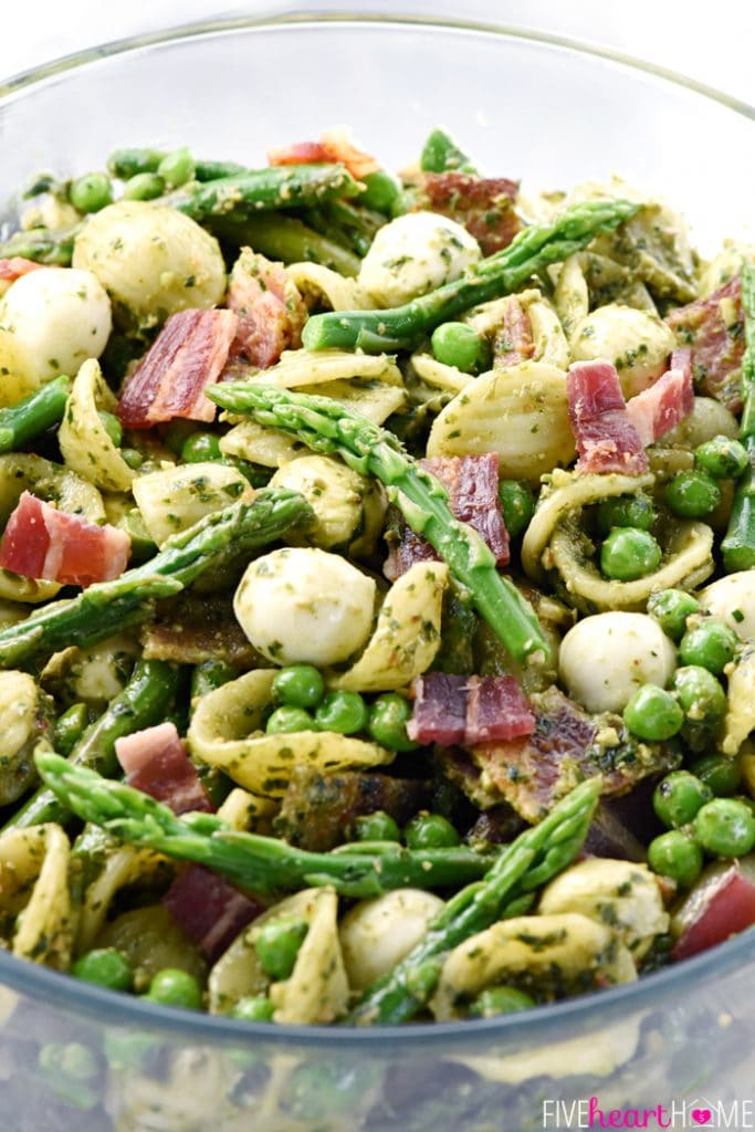 Pasta, bacon, peas, asparagus, mozzarella balls all served in a clear bow. 