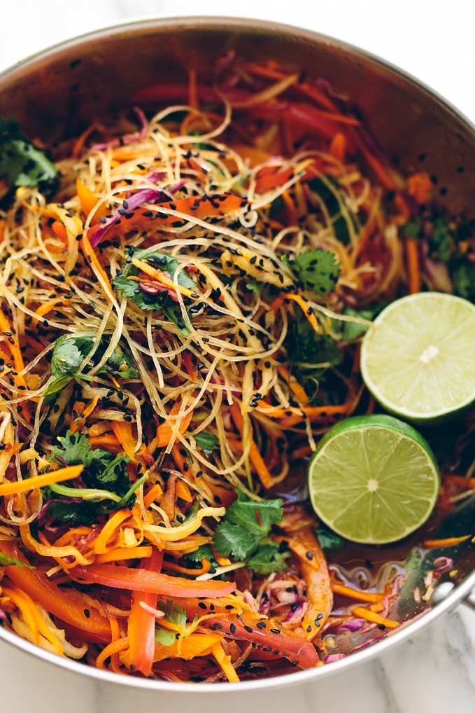 Pasta with glass noodles, lime slices, cilantro, and sliced carrots in a bowl.
