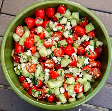 Cucumber, cherry tomatoes, mint and feta cheese all in bowl.